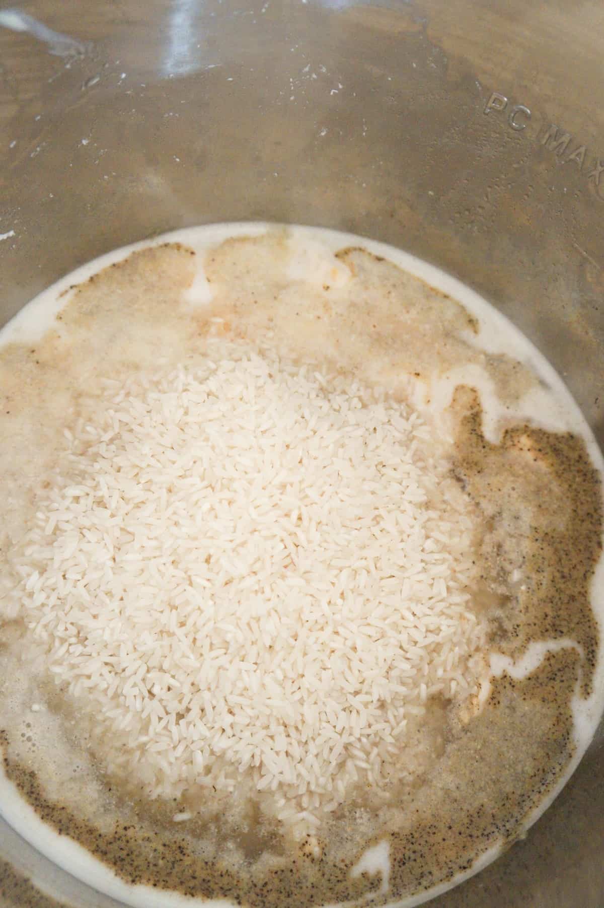 long grain white rice on top of chicken and water in an Instant Pot