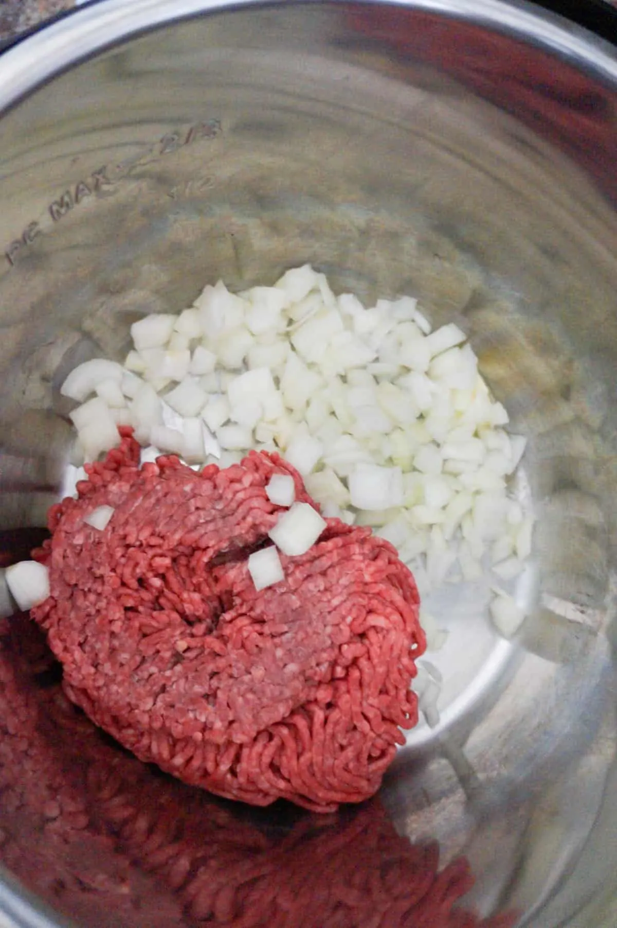 raw ground beef and diced onions in an Instant Pot