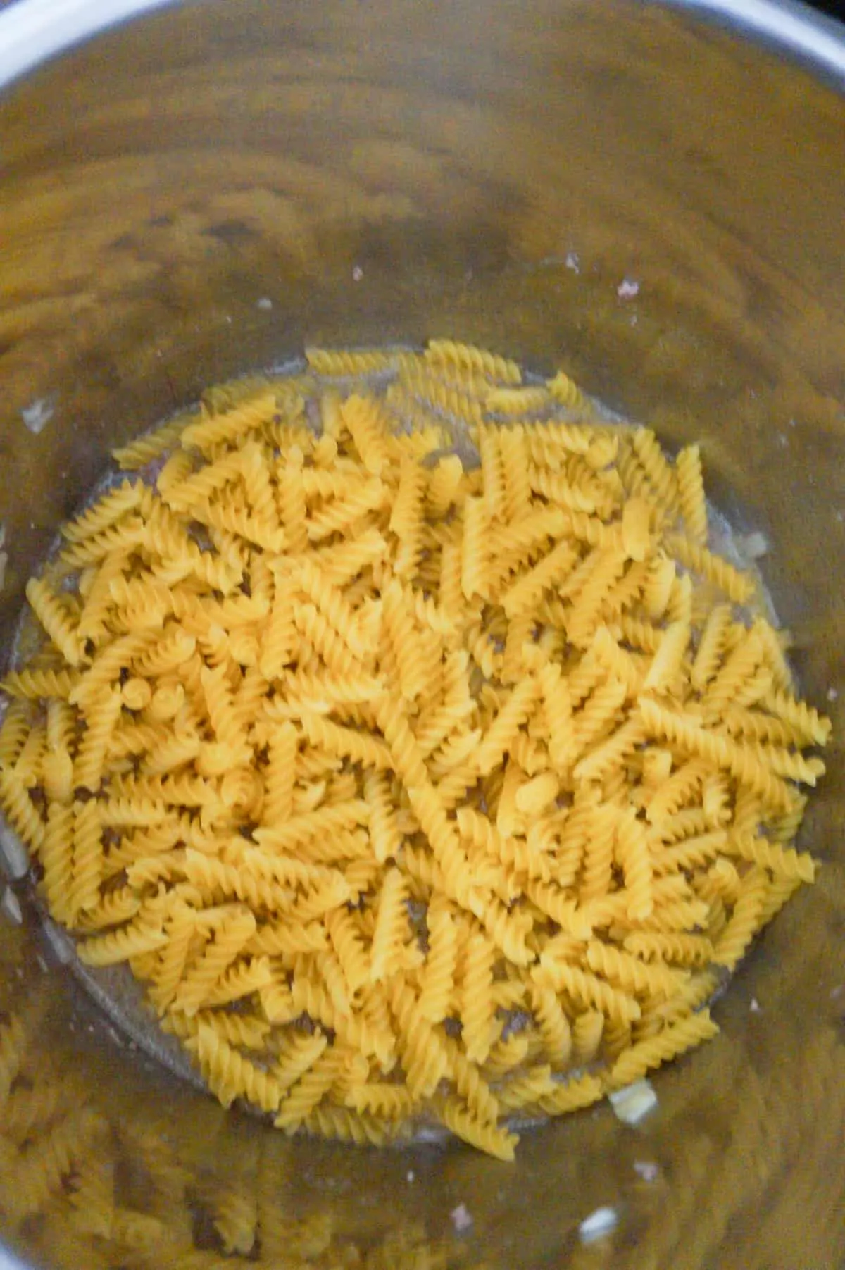 uncooked fusilli noodles in water in an Instant Pot