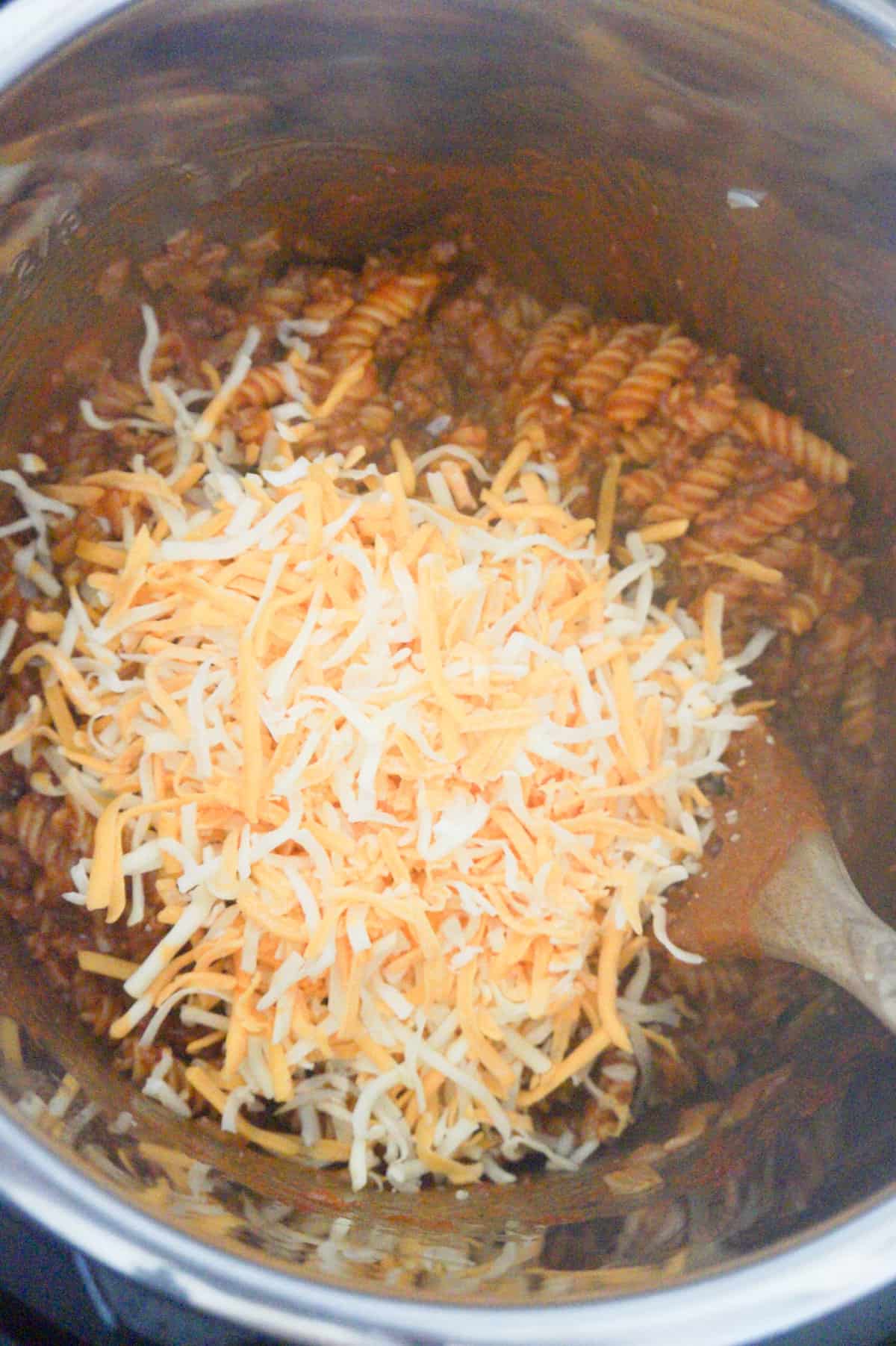 shredded mozzarella and cheddar cheese on top of sloppy joe pasta in an Instant Pot