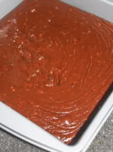 Scraping fudge into the pan.