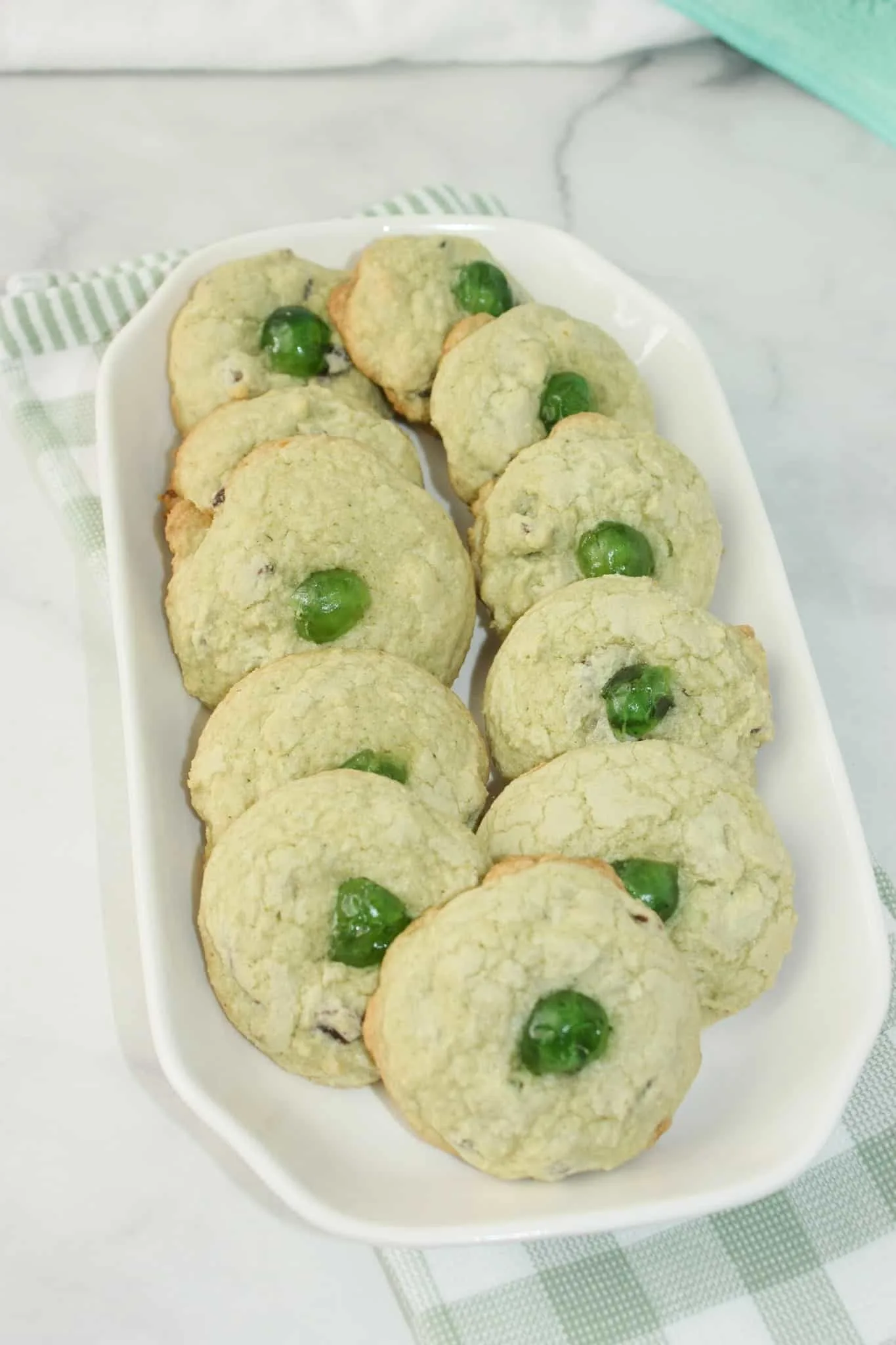 Mint Chocolate Chip Cookies are a tasty variation to traditional chocolate chip cookies.  Add some green colouring, mint chips and green cherries to give these cookies a festive flair for St. Patrick's Day or for your Holiday dessert trays!