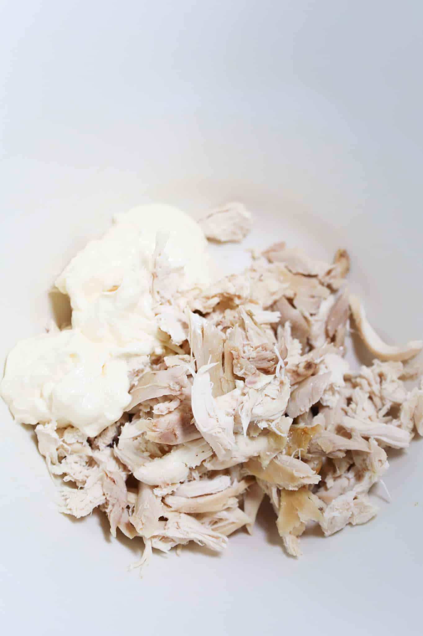 mayo and shredded rotisserie chicken in a mixing bowl