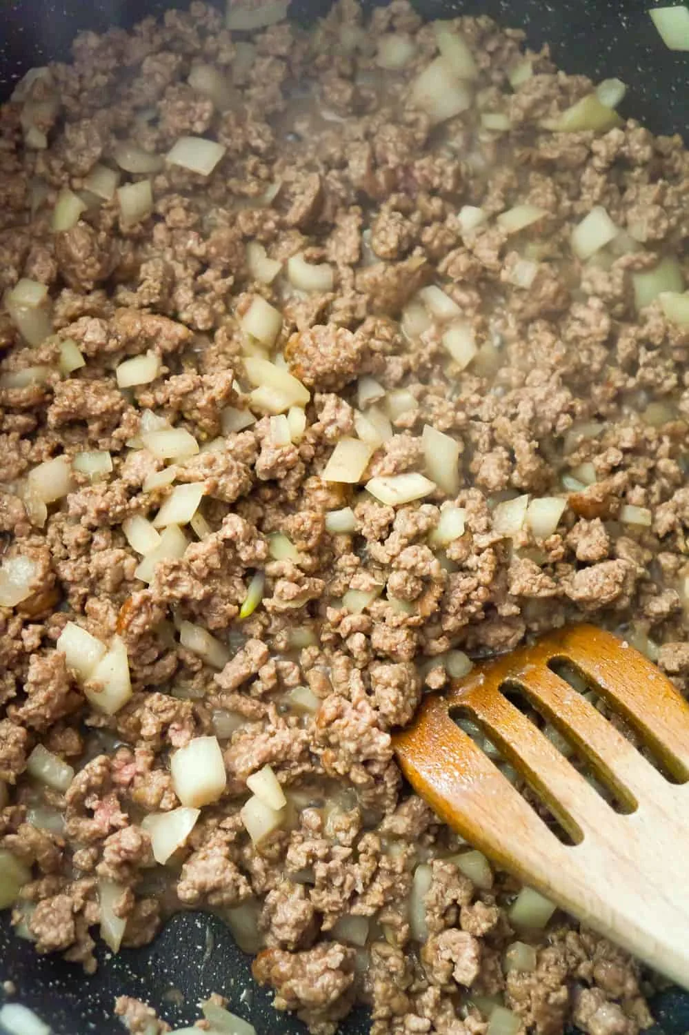 cooked ground beef and diced onions in a skillet
